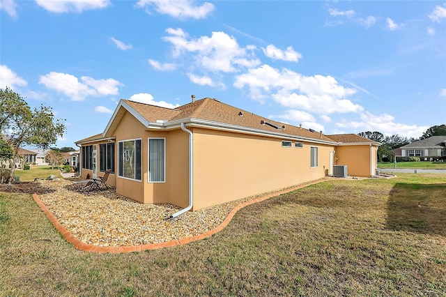 view of side of home with central AC unit and a yard