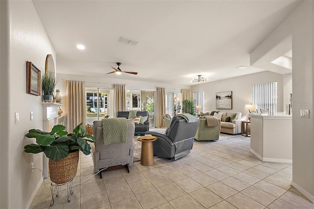 living area featuring light tile patterned floors, visible vents, baseboards, and ceiling fan