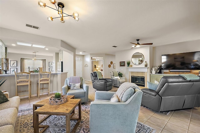 living area with light tile patterned floors, visible vents, ceiling fan, and a tile fireplace