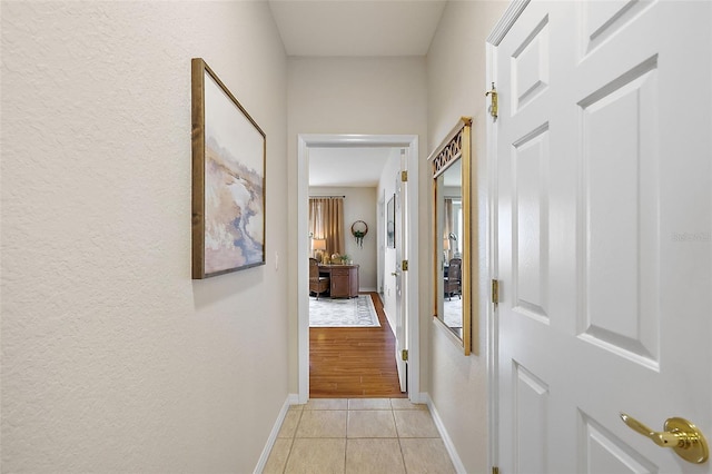 corridor with light tile patterned floors and baseboards