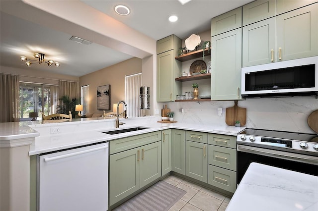 kitchen featuring visible vents, green cabinets, a peninsula, white appliances, and a sink