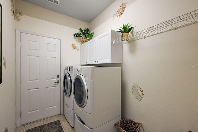 clothes washing area with visible vents, light tile patterned floors, cabinet space, and independent washer and dryer