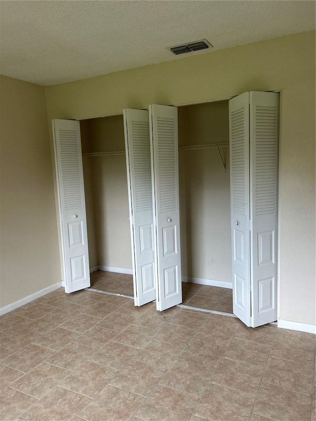 unfurnished bedroom with two closets and a textured ceiling