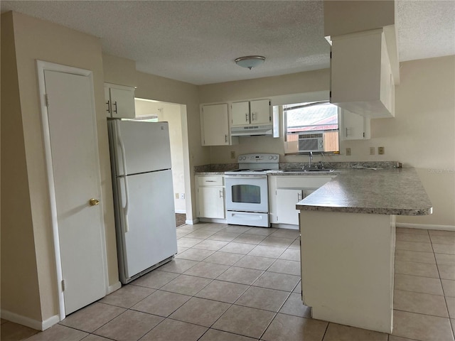 kitchen with light tile patterned floors, white appliances, kitchen peninsula, and white cabinets