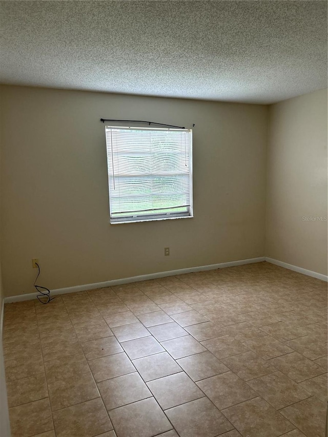 tiled empty room with a textured ceiling