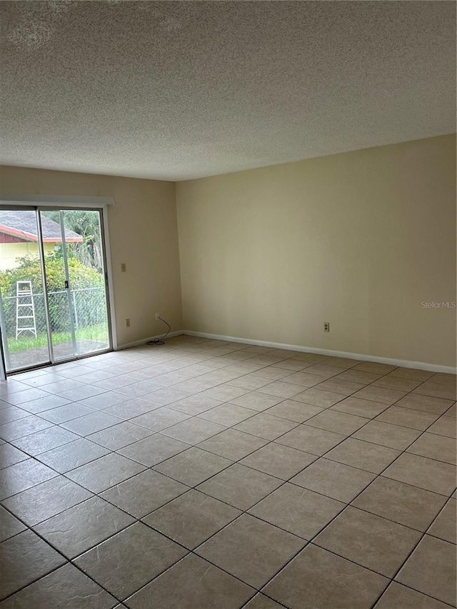 tiled empty room with a textured ceiling