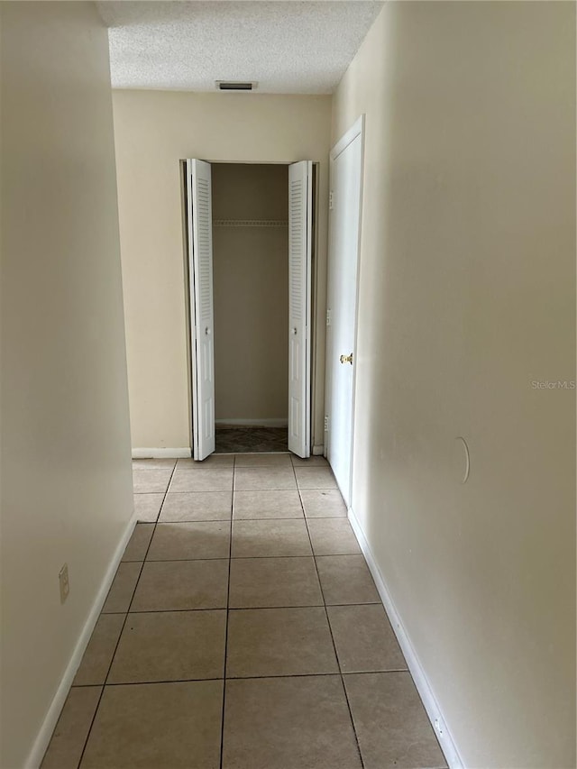 hallway featuring a textured ceiling and light tile patterned flooring