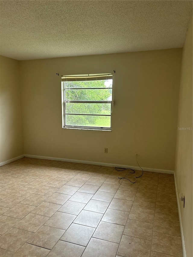 tiled empty room with a textured ceiling