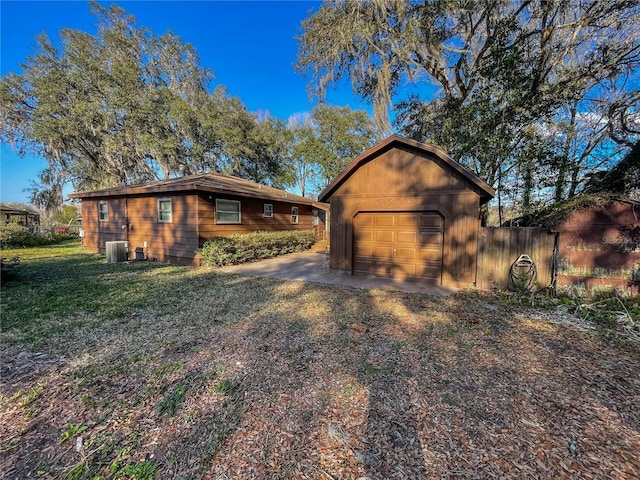 view of property exterior with an outbuilding, a garage, central AC, and a lawn