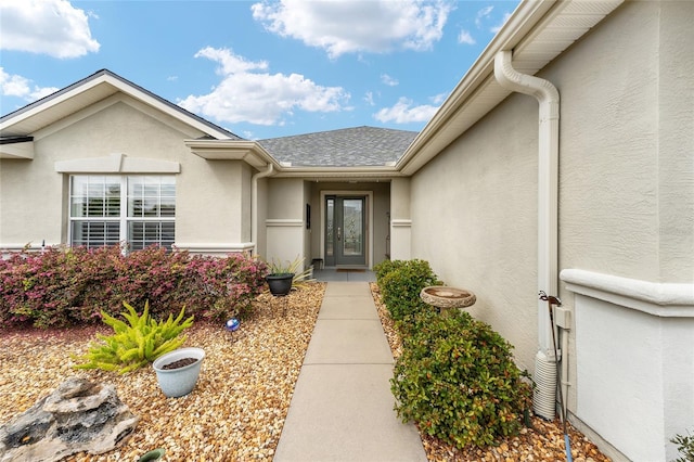 doorway to property featuring roof with shingles and stucco siding