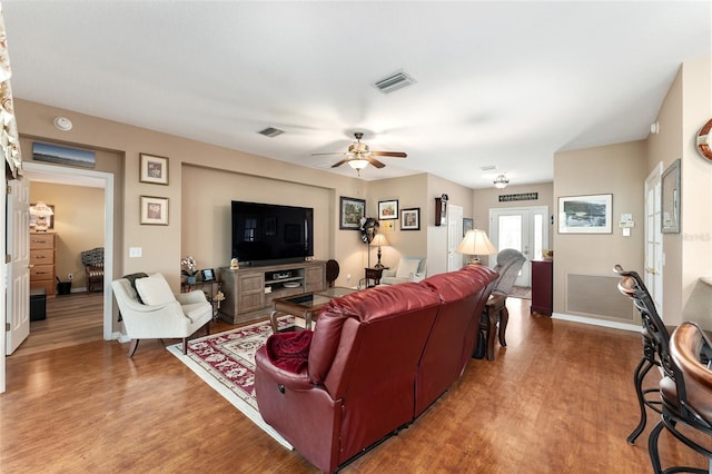 living area featuring baseboards, visible vents, and wood finished floors