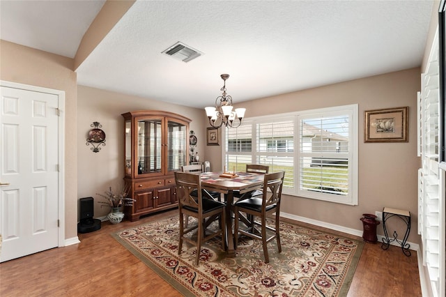 dining room featuring baseboards, visible vents, a chandelier, and wood finished floors