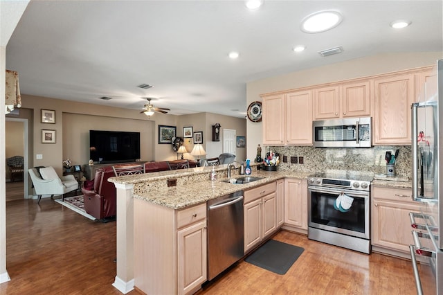 kitchen with a peninsula, a sink, visible vents, open floor plan, and appliances with stainless steel finishes