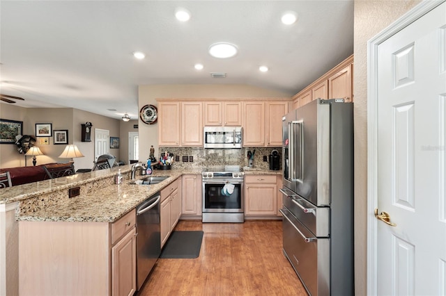 kitchen featuring a sink, stainless steel appliances, a peninsula, and light brown cabinets