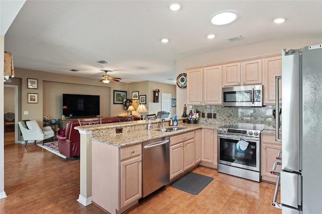 kitchen with visible vents, open floor plan, a peninsula, stainless steel appliances, and light brown cabinets