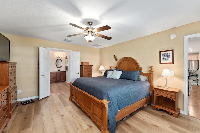 bedroom with visible vents, light wood-style flooring, and stainless steel refrigerator