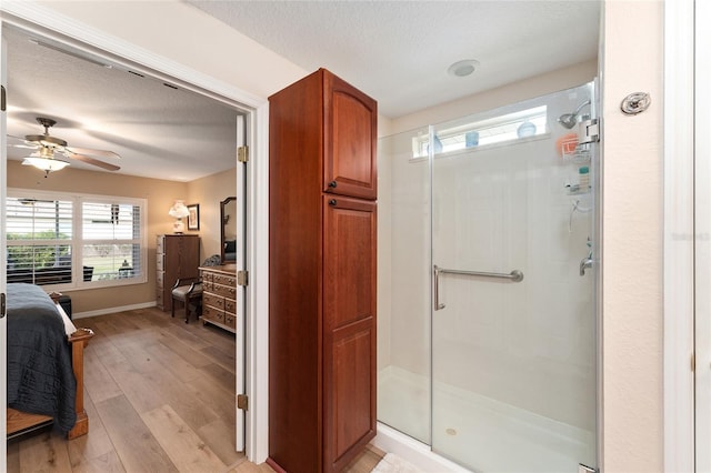 ensuite bathroom featuring ensuite bathroom, a stall shower, wood finished floors, and a textured ceiling