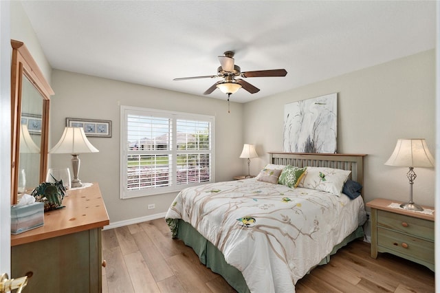 bedroom with light wood finished floors, a ceiling fan, and baseboards