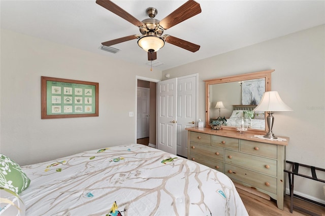 bedroom featuring a ceiling fan, a closet, visible vents, and wood finished floors