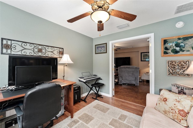 office space with a ceiling fan, baseboards, visible vents, and wood finished floors