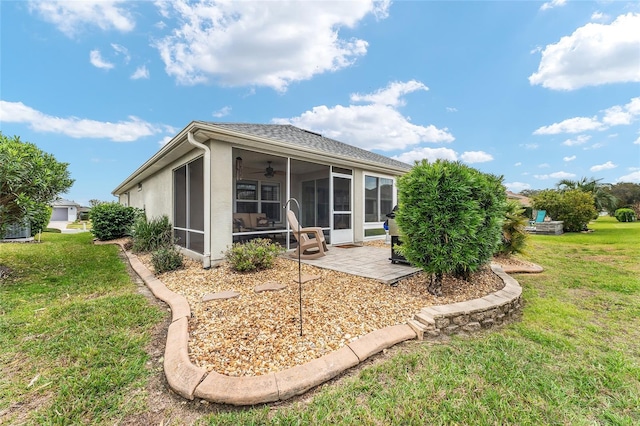 rear view of house featuring a sunroom, a patio area, a yard, and stucco siding