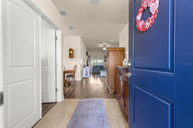 tiled foyer entrance with a textured ceiling and ceiling fan