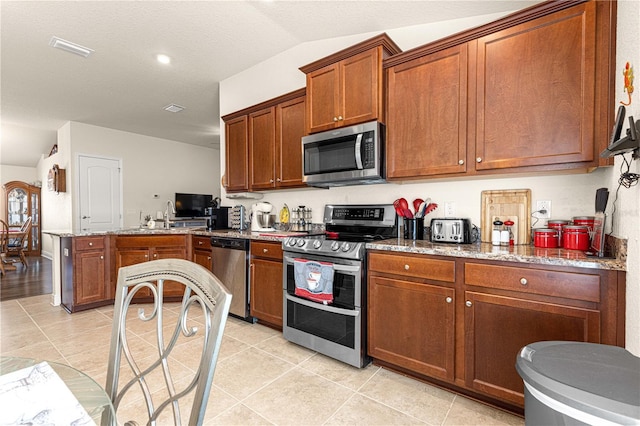 kitchen with light stone counters, sink, stainless steel appliances, and light tile patterned flooring