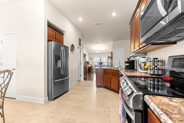 kitchen featuring light tile patterned flooring, sink, light stone counters, appliances with stainless steel finishes, and kitchen peninsula