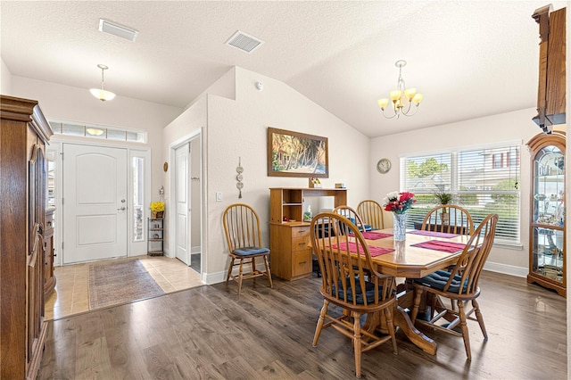 dining room featuring wood-type flooring, a textured ceiling, vaulted ceiling, and a chandelier