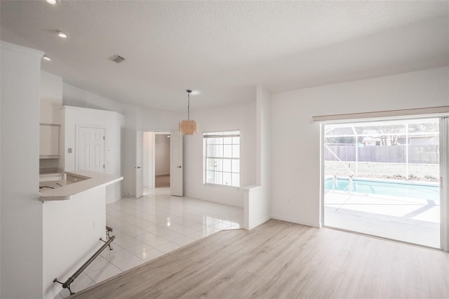 unfurnished living room with light wood-type flooring and a textured ceiling