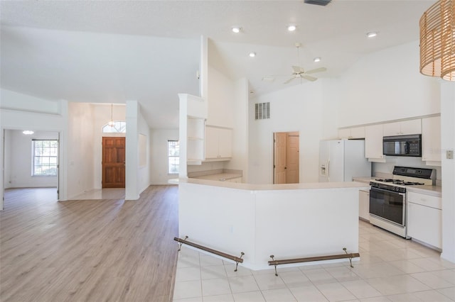 kitchen with white appliances, a wealth of natural light, light wood-type flooring, and white cabinets