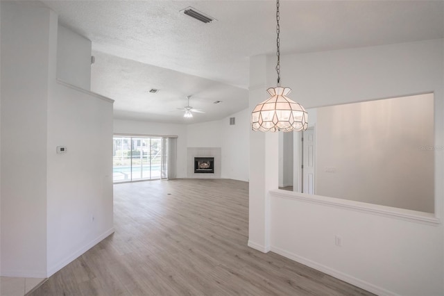 unfurnished living room featuring wood-type flooring, lofted ceiling, ceiling fan, and a textured ceiling