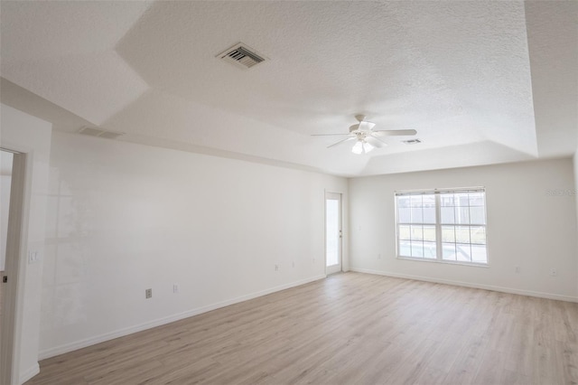 unfurnished room featuring ceiling fan, a raised ceiling, light hardwood / wood-style flooring, and a textured ceiling