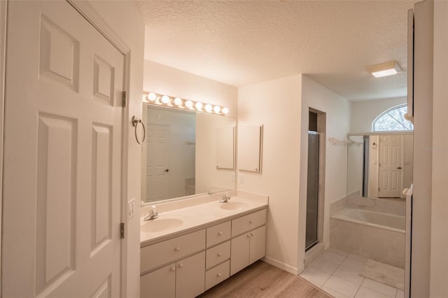 bathroom with vanity, independent shower and bath, hardwood / wood-style floors, and a textured ceiling