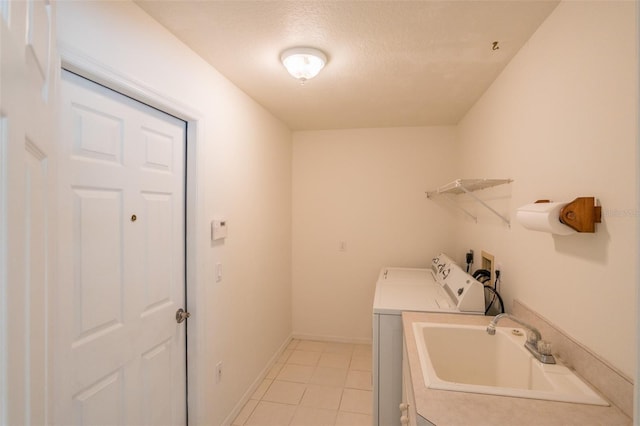 clothes washing area with sink, washing machine and dryer, a textured ceiling, and light tile patterned flooring