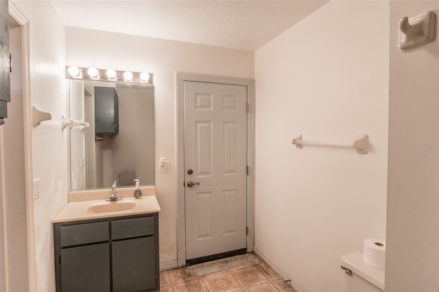 bathroom featuring vanity, a textured ceiling, and toilet