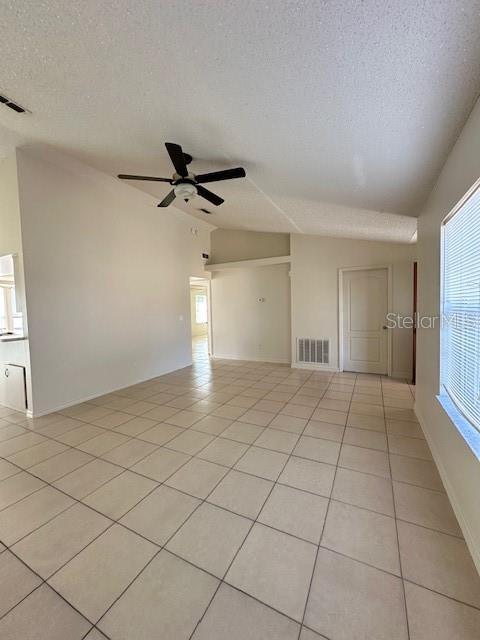 tiled spare room with lofted ceiling, a textured ceiling, and ceiling fan