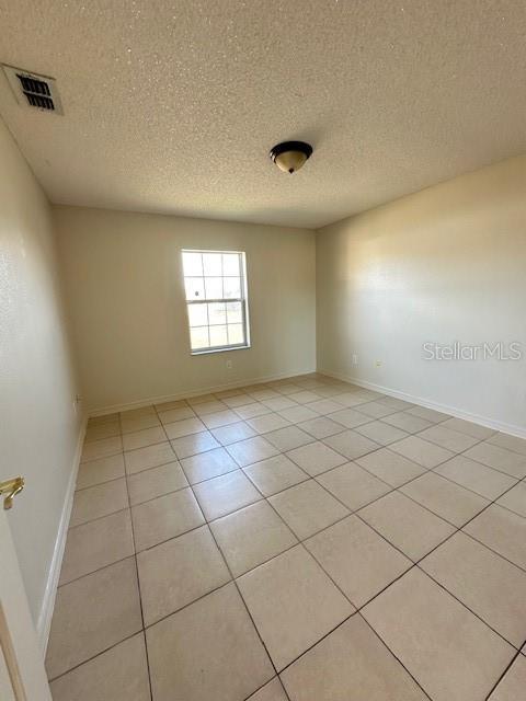 empty room with light tile patterned floors and a textured ceiling