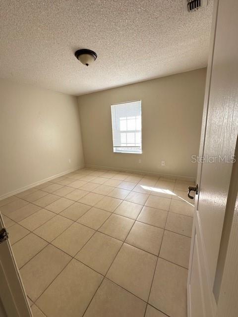 empty room with light tile patterned floors and a textured ceiling