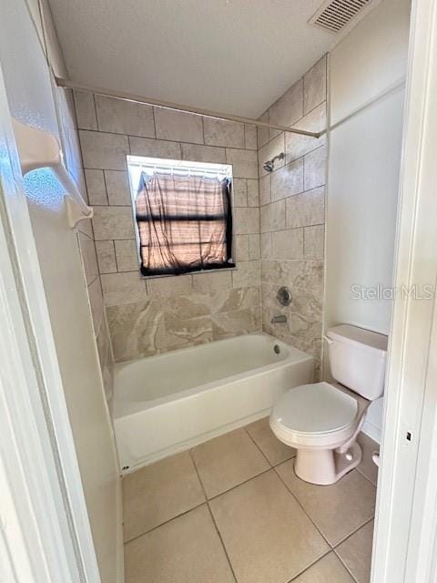 bathroom featuring tiled shower / bath, tile patterned floors, and toilet