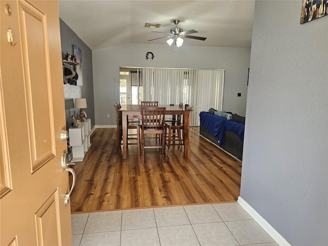 dining room featuring lofted ceiling, ceiling fan, light tile patterned flooring, visible vents, and baseboards