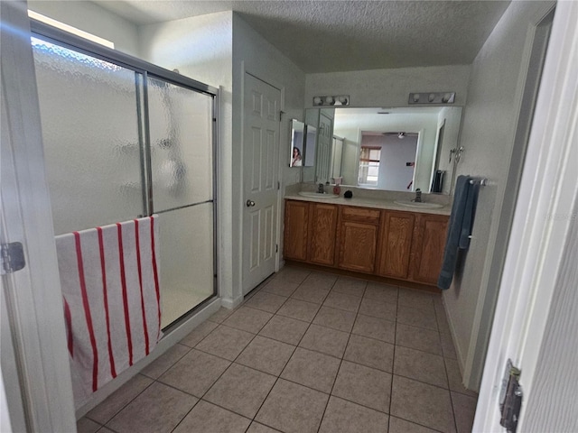 full bath with tile patterned floors, a stall shower, and a sink