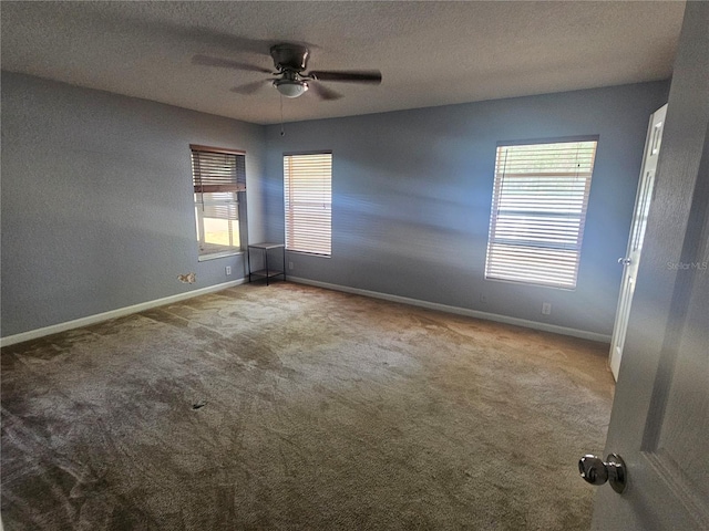 carpeted empty room with baseboards, a ceiling fan, and a textured ceiling