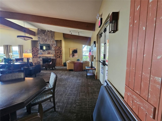 dining room featuring dark carpet, beam ceiling, french doors, and a fireplace