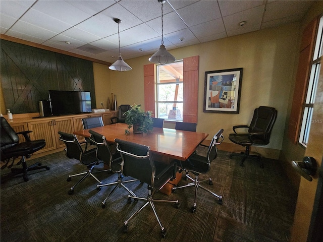carpeted dining space featuring baseboards and a drop ceiling