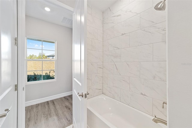 bathroom with hardwood / wood-style flooring and tiled shower / bath combo