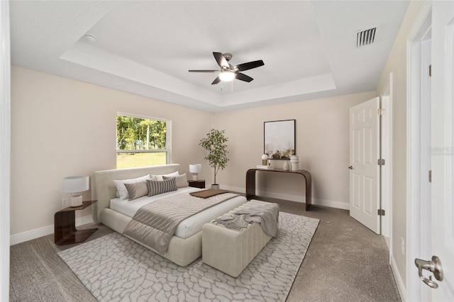 carpeted bedroom featuring ceiling fan and a raised ceiling