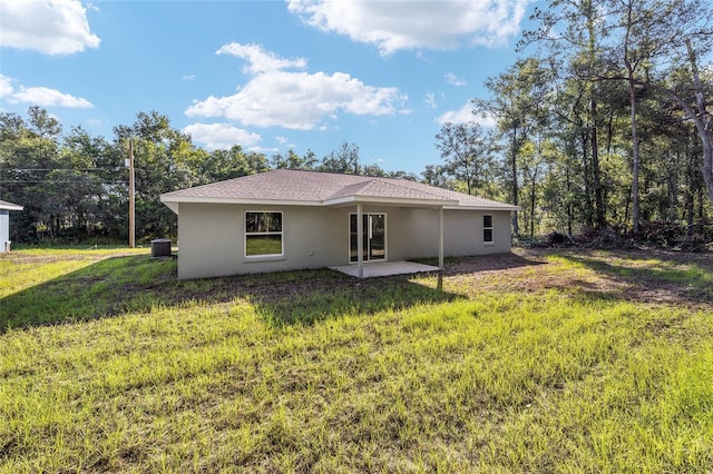 back of property with a patio, a lawn, and central AC