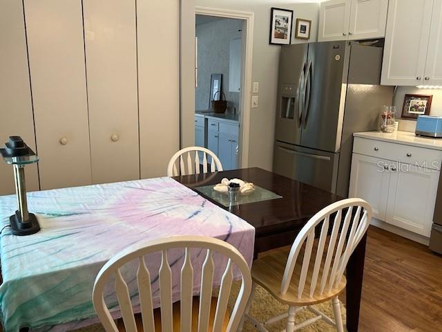 kitchen with stainless steel fridge with ice dispenser, hardwood / wood-style floors, and white cabinets