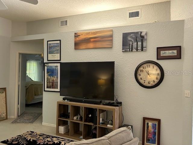 living room with a textured ceiling and ceiling fan